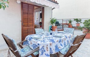 An outdoor patio with a table set for dining, surrounded by potted plants and a brick wall. - Beautiful apartment in Rovinj with WiFi (Rovinj)
