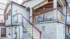 Ein mehrstöckiges Gebäude mit einer steinernen Fassade, einer roten Metalltreppe und einem Balkon mit Glastrennwand.