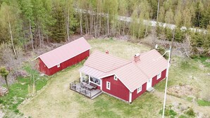 A red barn with a porch and a smaller adjacent structure, surrounded by forest. - Cozy home in Ryd with WiFi (Ryd)