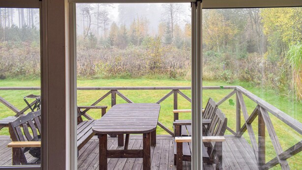 A wooden deck with a table and benches, overlooking a forested area. - Cozy home in Ryd with WiFi (Ryd)