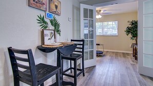 Un coin repas avec deux chaises noires, une petite table et une plante en pot.