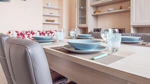 A dining area with a long table set for four, featuring blue plates and clear glasses. - 2 bedroom amazing apartment in Guspini (Guspini)