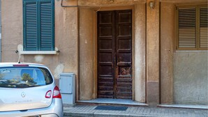 A white car parked in front of a building with a large wooden door and green shutters. - 2 bedroom amazing apartment in Guspini (Guspini)