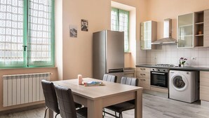 A modern kitchen with a dining area, featuring a refrigerator, oven, washing machine, and a window with a view. - 2 bedroom amazing apartment in Guspini (Guspini)
