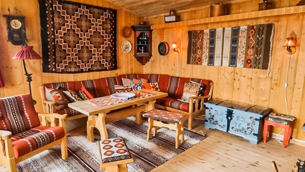 Um quarto aconchegante com piso de madeira, um conjunto de sofá, uma mesa pequena e um tapete estampado.