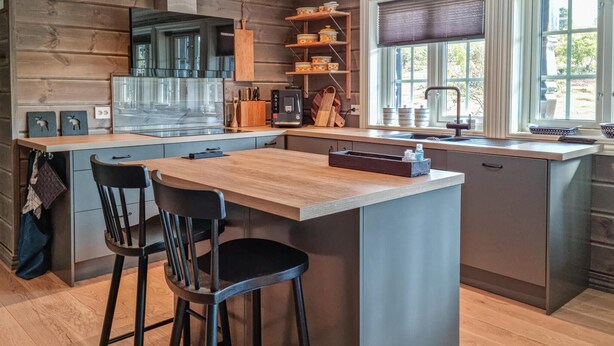 A modern kitchen with a central island, bar stools, wooden cabinetry, and a window providing natural light. - Stunning home in Hovden i setesdal (Hovden i setesdal)