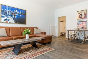 A modern living room with a brown sofa, a coffee table, and a dining area with a table and chairs.