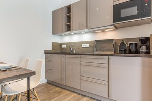 Une cuisine moderne dotée d’appareils électroménagers intégrés, d’un plan de travail en bois et d’un coin repas avec une table et des chaises.