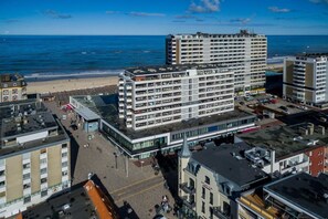 A multi-story hotel with a modern architectural design, located near a beach with a view of the ocean.