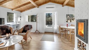 Una habitación acogedora con techo de madera, chimenea, zona de comedor y vistas al exterior.