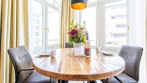 Ett runt träbord med en vas med blommor, en vinflaska och ett glas.