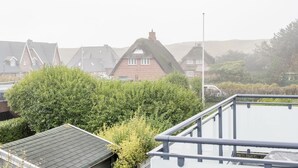 Un quartier résidentiel où l’on trouve des maisons aux toits pentus et aux pignons recouverts de chaume, le tout entouré d’une végétation luxuriante.