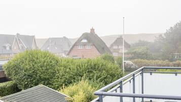 A residential area with houses featuring steep roofs and thatched gables, surrounded by dense greenery.