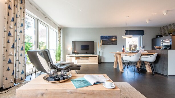 Ein modernes Wohnzimmer mit großem Fenster, Essbereich und Küche.