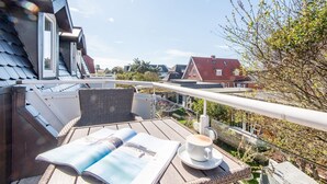 Una terraza en la azotea con una mesa, sillas, una taza de café y una revista.
