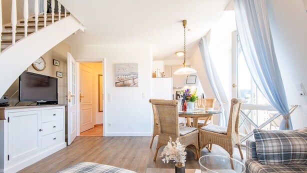 Una sala de estar moderna con comedor, escalera y cocina.