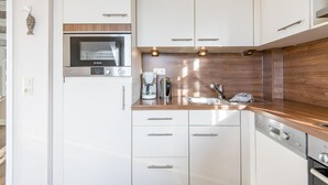 Eine moderne Küche mit weißen Schränken, einem Bosch-Backofen, einer Kaffeemaschine und einem Spülbecken.