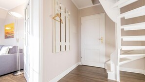 Ein modernes Interieur mit Treppe, einer weißen Tür und einem grauen Sofa.