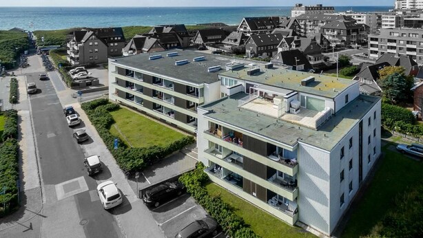 Un moderno edificio a più piani con tetto piatto, parcheggio e vista sul mare.