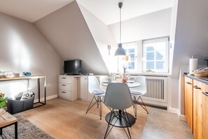 Une cuisine moderne avec un coin repas, un téléviseur et une grande fenêtre donnant sur la ville.