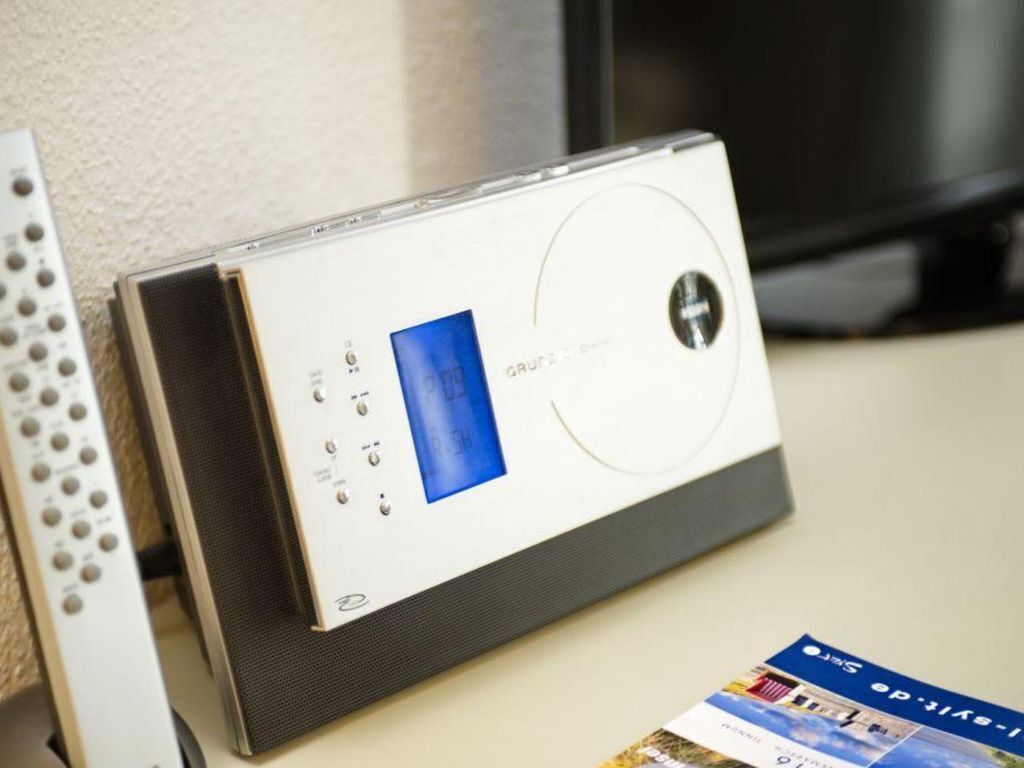 Ein digitales Thermostat an der Wand, eine Fernbedienung und eine Broschüre auf einem Tisch.