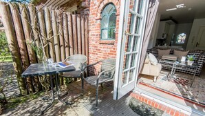 A patio with wicker furniture, a glass table, and a brick wall. - Old town gate in Friesenpark, apartment 7 (Sylt)