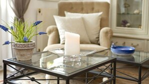 A glass-top table with a white candle, a potted plant with blue flowers, and a blue bowl. - Old town gate in Friesenpark, apartment 7 (Sylt)