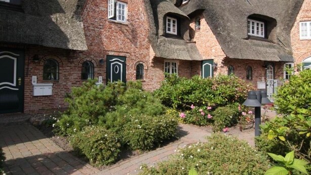A traditional brick building with thatched roofs and green shutters. - Old town gate in Friesenpark, apartment 7 (Sylt)