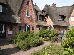 A traditional brick building with thatched roofs and green shutters.