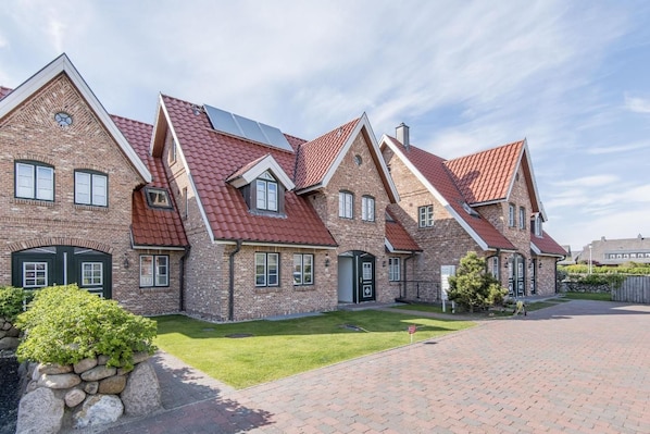 A row of brick houses with red-tiled roofs and green lawns. - House Norderstraße 55, Whg. 9 (Sylt)