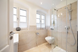 A modern bathroom with a glass-enclosed shower, a toilet, and two windows with blinds. - House Norderstraße 55, Whg. 9 (Sylt)
