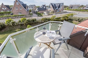 A balcony with a glass enclosure, a round table, and two chairs. - House Norderstraße 55, Whg. 9 (Sylt)
