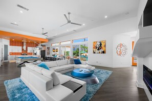 A modern living room with a white sectional sofa, a blue coffee table, and a fireplace. - PS Playground - Putt Chip - Horseshoe - Corn Hole - Pool Table (Palm Springs)