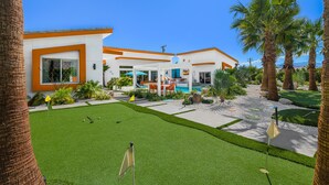 A modern house with a pool, a well-maintained lawn, and palm trees. - PS Playground - Putt Chip - Horseshoe - Corn Hole - Pool Table (Palm Springs)