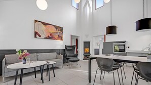 En moderne stue med en grå sofa, et rundt sofabord og et maleri på væggen.