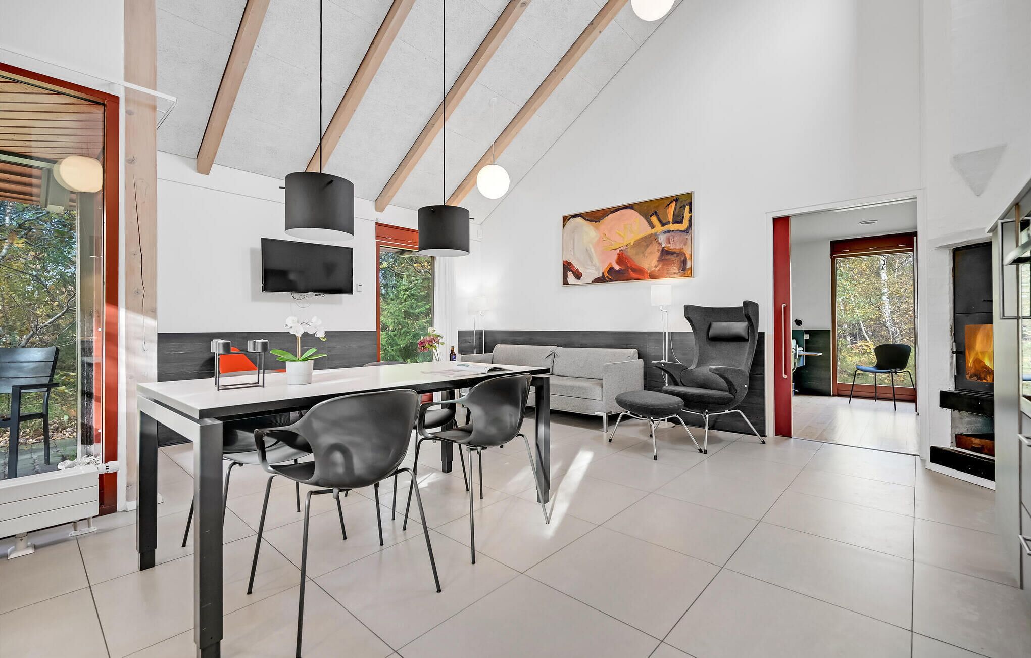 A modern dining area with a large table, black chairs, and a fireplace.