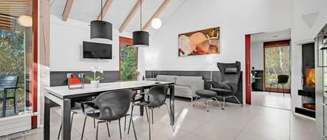 A modern dining area with a large table, black chairs, and a fireplace.