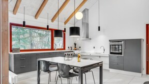 A modern kitchen with a large island, a dining area with chairs, and a view through the window. - Nice home in Grenaa with WiFi (Grenaa)