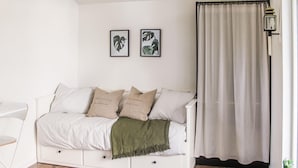 A white sofa with multiple cushions and a green throw blanket, a white chair, and a floor lamp.