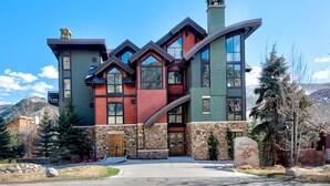 A multi-story house with a stone facade, large windows, and a prominent chimney.