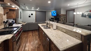 A modern kitchen with wooden cabinets, granite countertops, and a built-in stove.