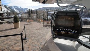 A chairlift at Riverfront Village with a view of snow-capped mountains.