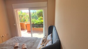 Une chambre avec un lit, une chaise et une vue sur un balcon agrémenté de plantes.