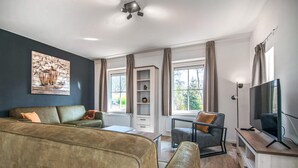 Una sala de estar moderna con sofá, sillón y mueble para televisión.
