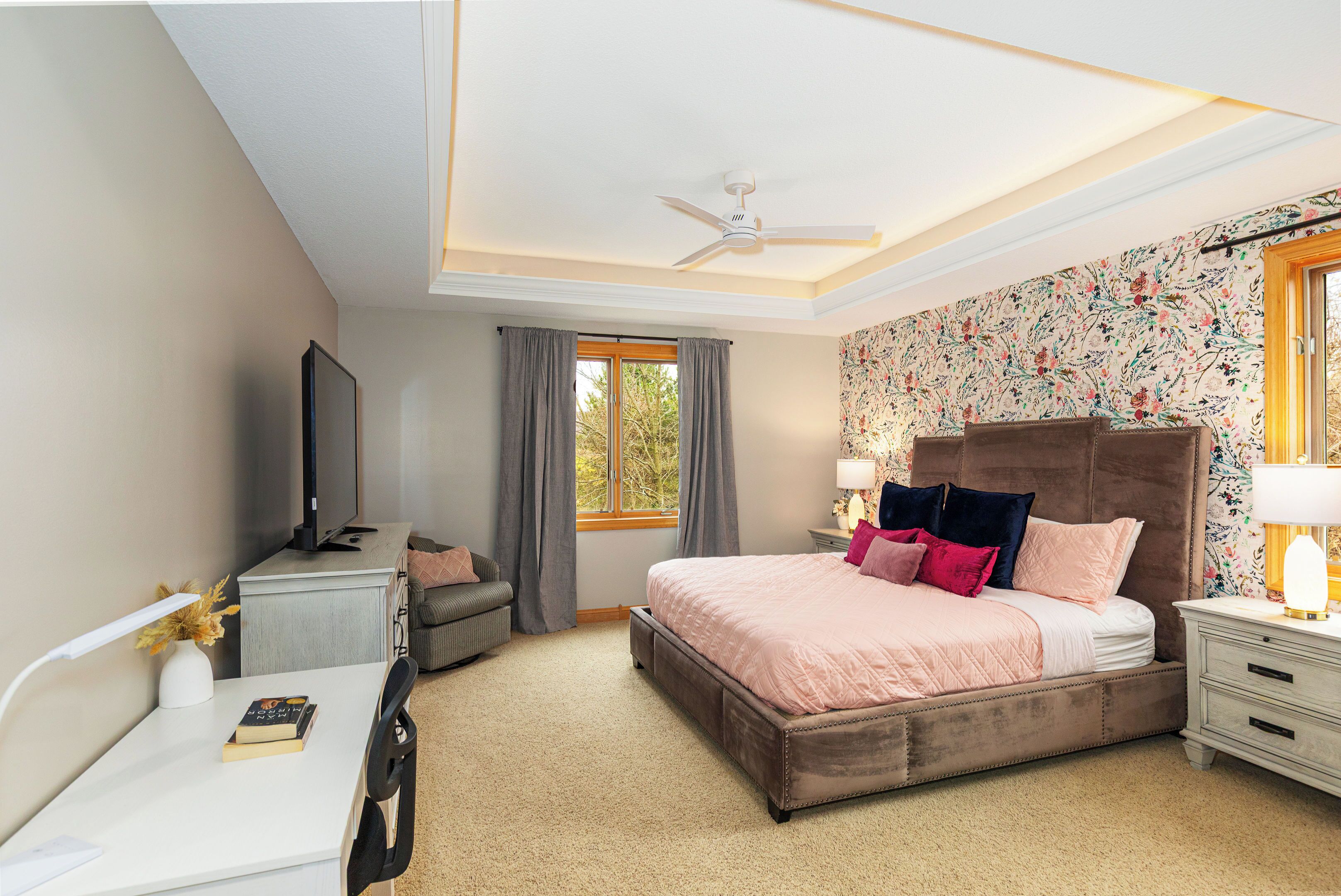 A bedroom with a bed, a desk, a chair, a television, and a window with curtains.