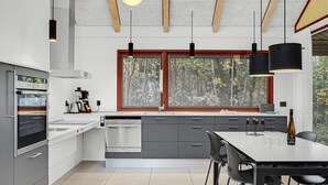Eine moderne Küche mit Einbauofen, Geschirrspüler und großem Fenster mit Jalousien.