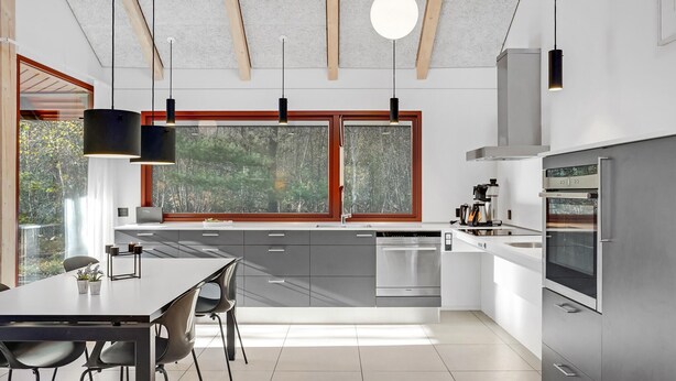 A modern kitchen with a large island, stainless steel appliances, and a view of trees through the windows. - 2 bedroom gorgeous home in Grenaa (Grenaa)