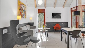 A modern living room with a grey sofa, a round coffee table, and a TV mounted on the wall. - 2 bedroom gorgeous home in Grenaa (Grenaa)