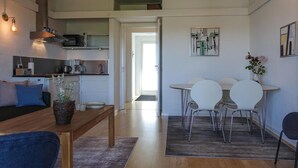 Una cucina moderna con forno integrato, macchina del caffè e bollitore sul piano di lavoro. C'è un'area pranzo con tavolo e sedie, e una panca con cuscini.