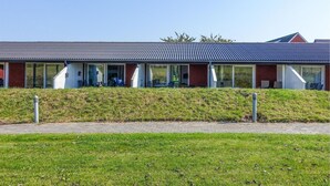 Un edificio moderno con tetto piatto, ampie finestre in vetro e un'area verde di fronte.